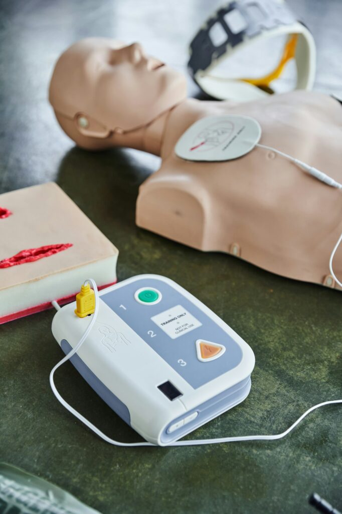 automated external defibrillator near wound care simulator, CPR manikin and neck brace on blurred