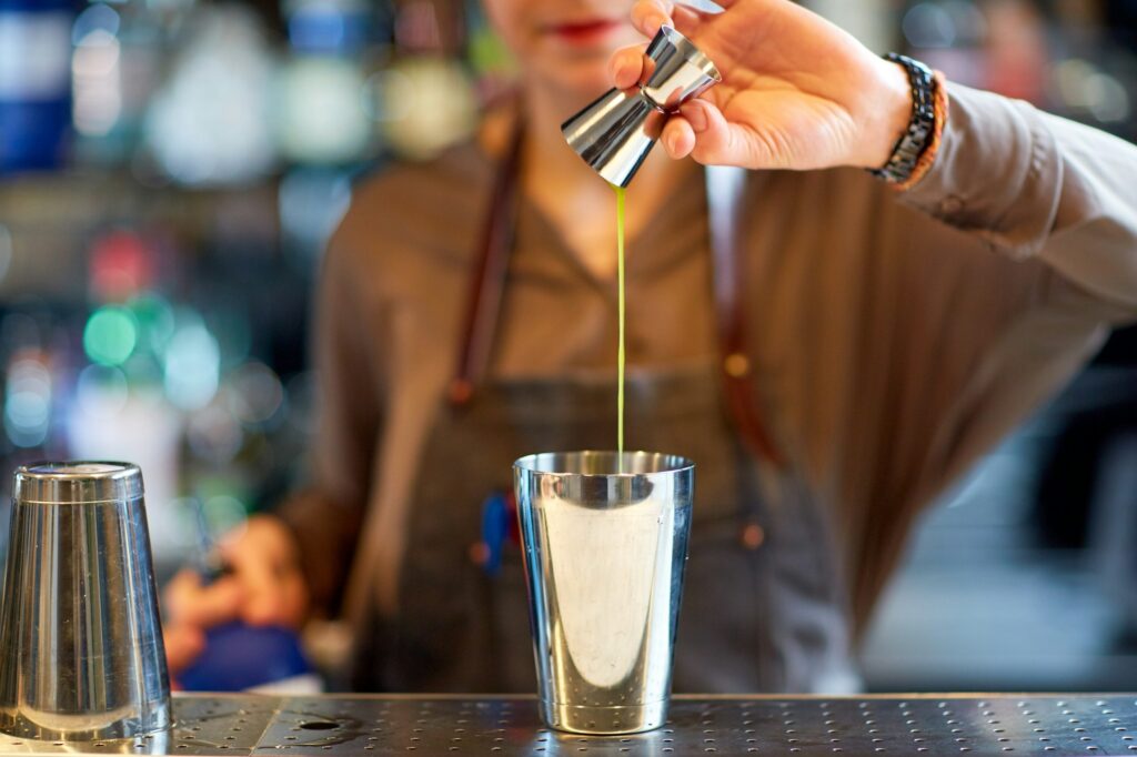 bartender with cocktail shaker and jigger at bar