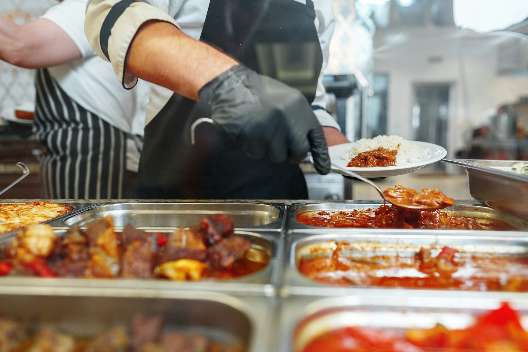 Chef Serving Freshly Cooked Dishes at a Restaurant Buffet During Lunchtime