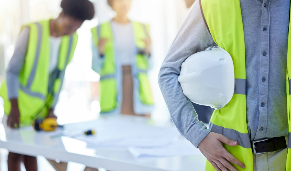 Construction worker, closeup and helmet with arm of engineer, builder or contractor. Industrial tea