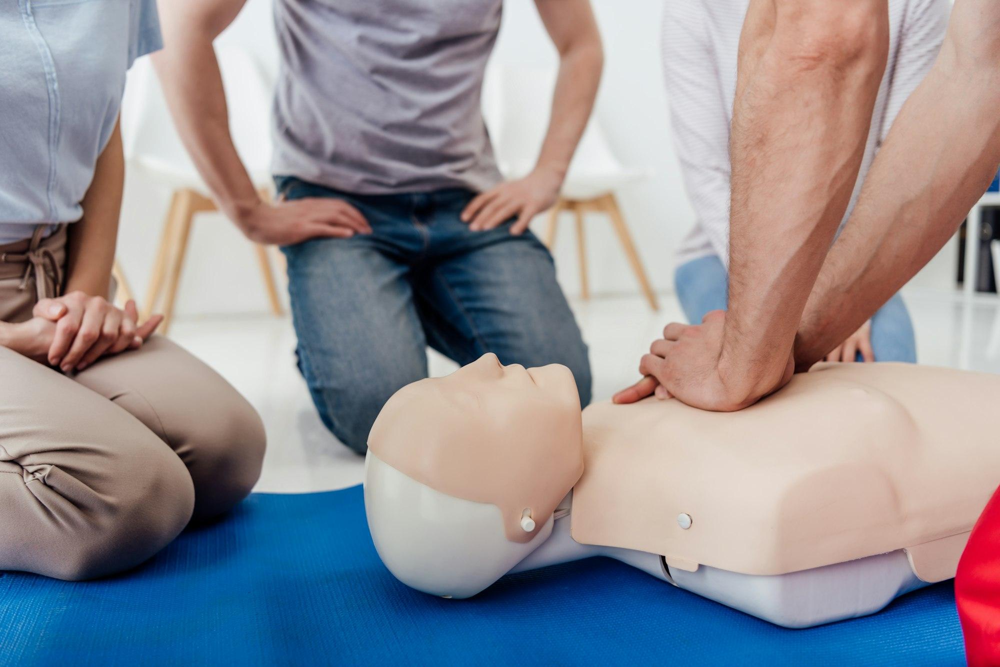 cropped view of group of people during first aid training with dummy