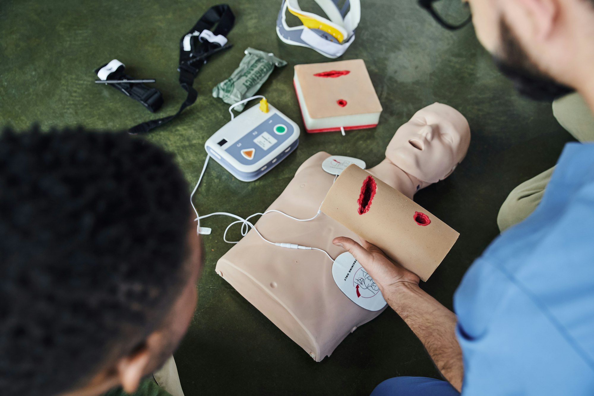 partial view of professional paramedic holding wound care simulator near african american man, CPR